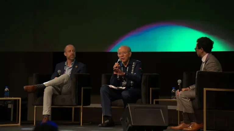 Panel de discusión en un festival con tres personas en el escenario